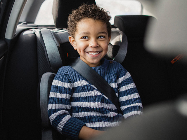 Smiling child in car seat with seatbelt fastened